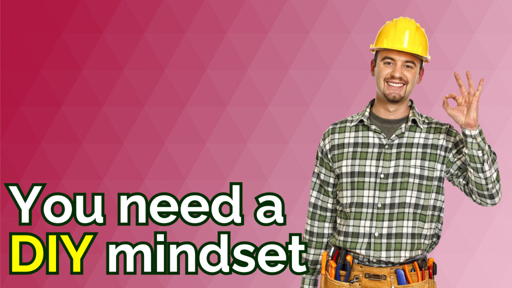 A smiling man wearing a yellow hard hat and tool belt gives an OK hand gesture, next to the text “You need a DIY mindset” on a pink geometric background.
